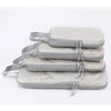 A stack of four light gray vertical travel organizer bags with fabric straps.