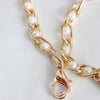 Gold chain strap with small white pearls, featuring an adjustable clasp.