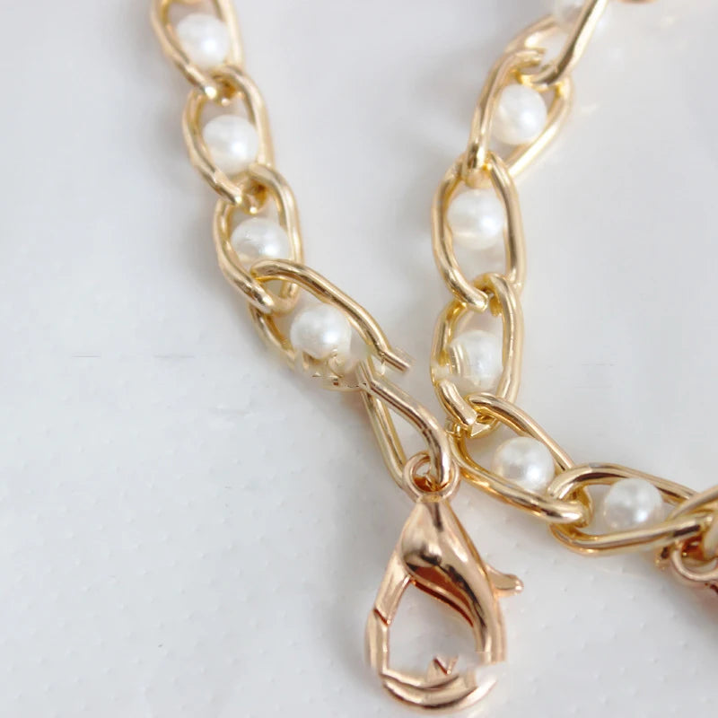Gold chain strap with small white pearls, featuring an adjustable clasp.
