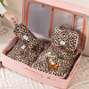 A pink travel makeup organizer box with a lid open, containing two leopard print storage bags.