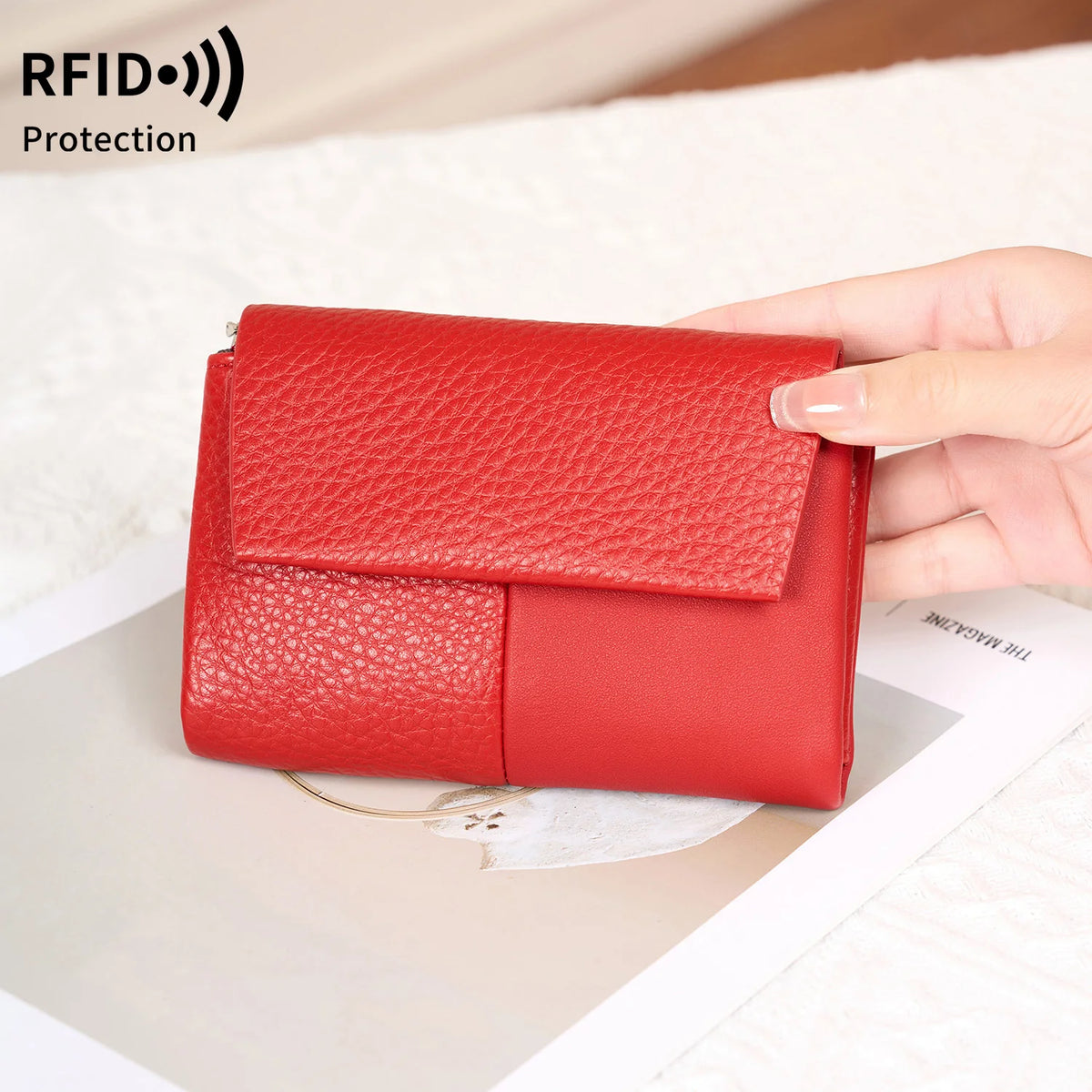 يد تمسك محفظة حمراء ثلاثية الطي لحجب بطاقات RFID مع سحاب على سطح فاتح.