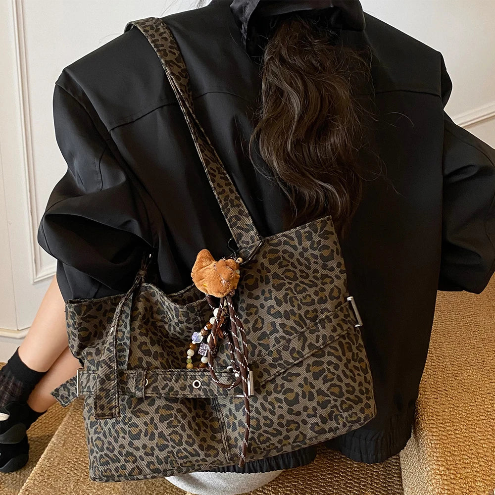 A person is holding a leopard print casual tote bag against a black jacket.