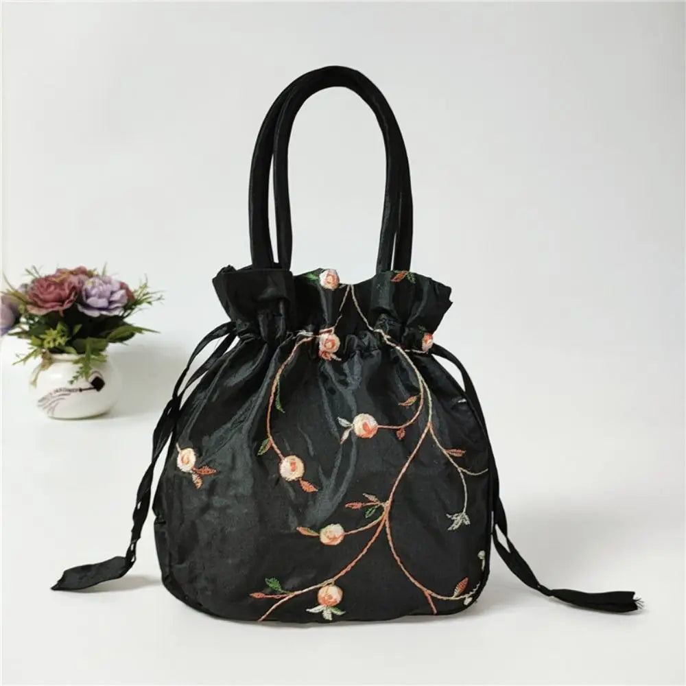 Clutch de terciopelo negro con lazo, bordado floral dorado y un adorno de tela floral