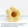 A pale yellow flower-shaped phone grip ring stand with small black dots on the surface.