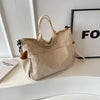 A beige corduroy multi-pocket tote bag with light tan straps is displayed on a white surface next to a framed sign.