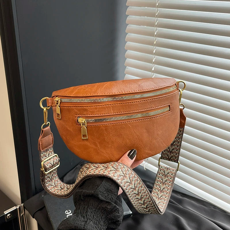 A brown PU leather crossbody bag with a gold-toned adjustable strap is displayed against a light background.