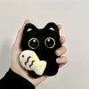 A black cat plush toy with yellow eyes and a white paw print charm being held by a hand.