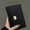A hand holds a black card holder wallet with a gold embossed cloud design.