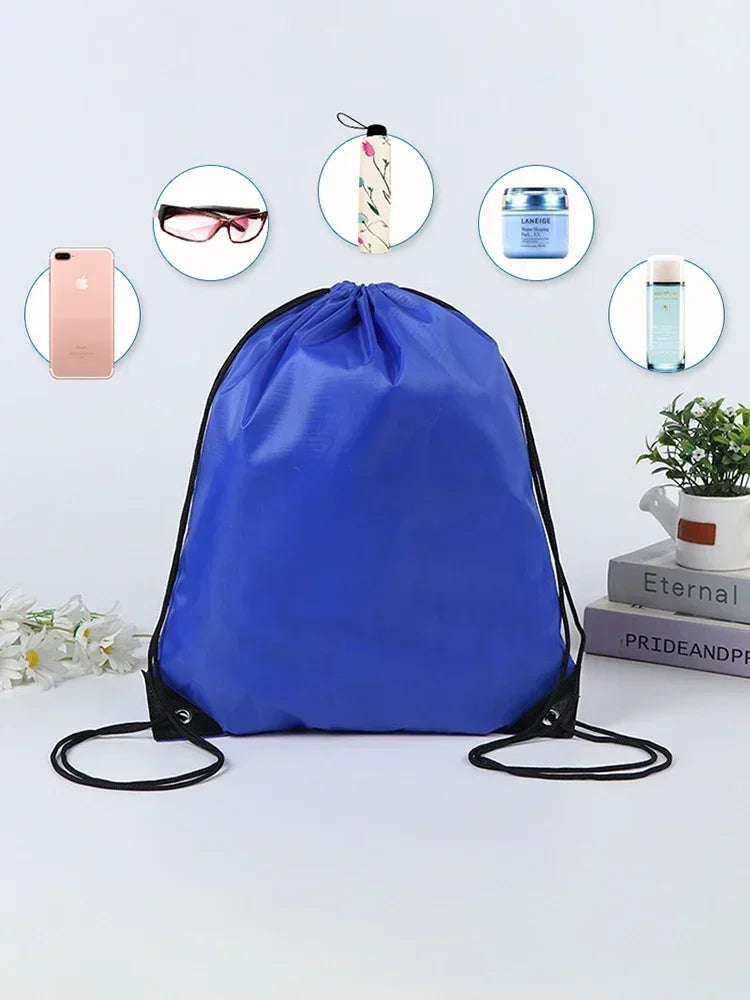 A royal blue drawstring backpack is shown with various items like a smartphone, sunglasses, and perfume bottles arranged arou