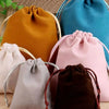 Colección de cinco bolsas de regalo de terciopelo suave con cordón en tonos naranja, azul, rosa, gris y marrón.