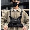 Un homme portant un masque noir et une veste beige tient un sac de sport noir multi-usage.
