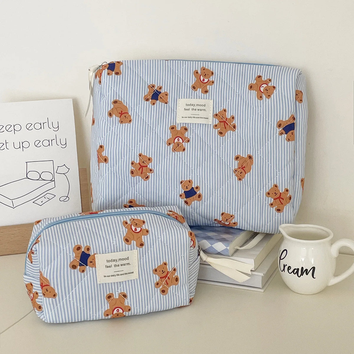 A light blue and white striped cosmetic makeup bag featuring small bear illustrations.
