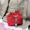 A red crystal-embellished evening clutch with a silver chain, resting on a light gray blazer.