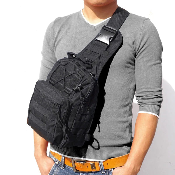 A person wearing a gray long-sleeved shirt and jeans is holding a black tactical sling backpack.