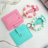 A pink and teal silicone bead and leather card wallet with decorative beaded straps.