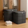 Deux sacs de rangement pliables et robustes gris foncé sur un plancher en bois.