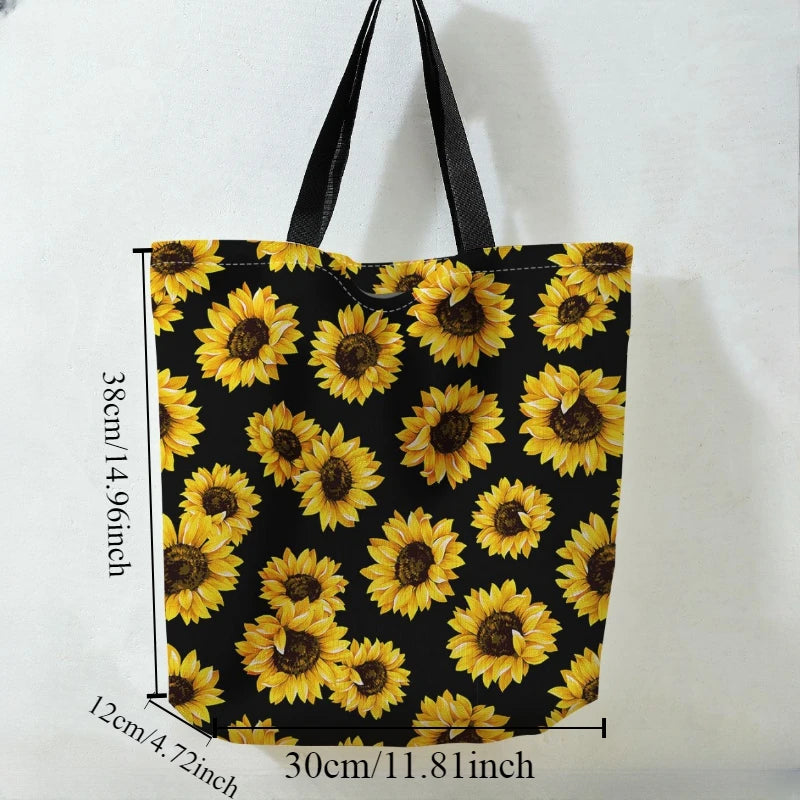 Black canvas tote bag featuring a repeating pattern of yellow sunflowers with black centers and green leaves.