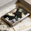 Art Deco metal card holder with a dark floral design resting in a light box.