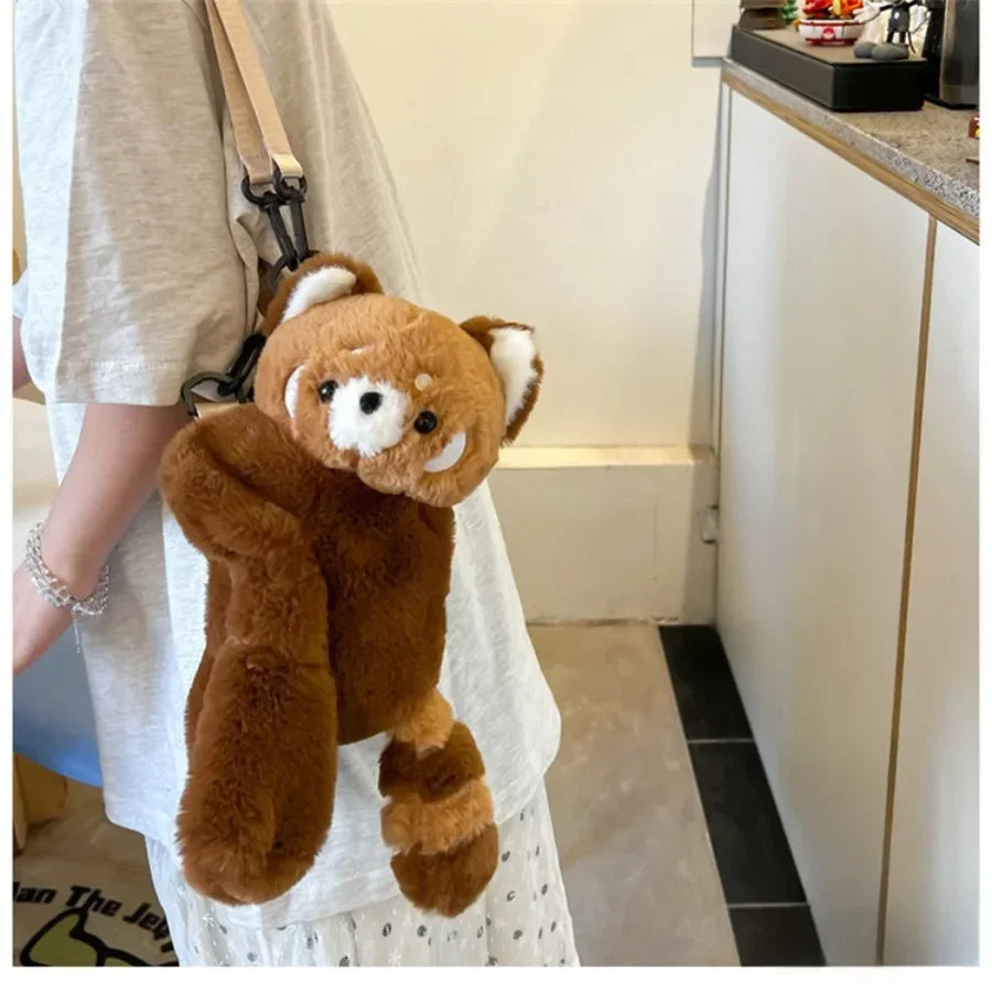 A brown red panda plush toy is displayed next to a white shirt, suggesting it is a soft furry crossbody bag.