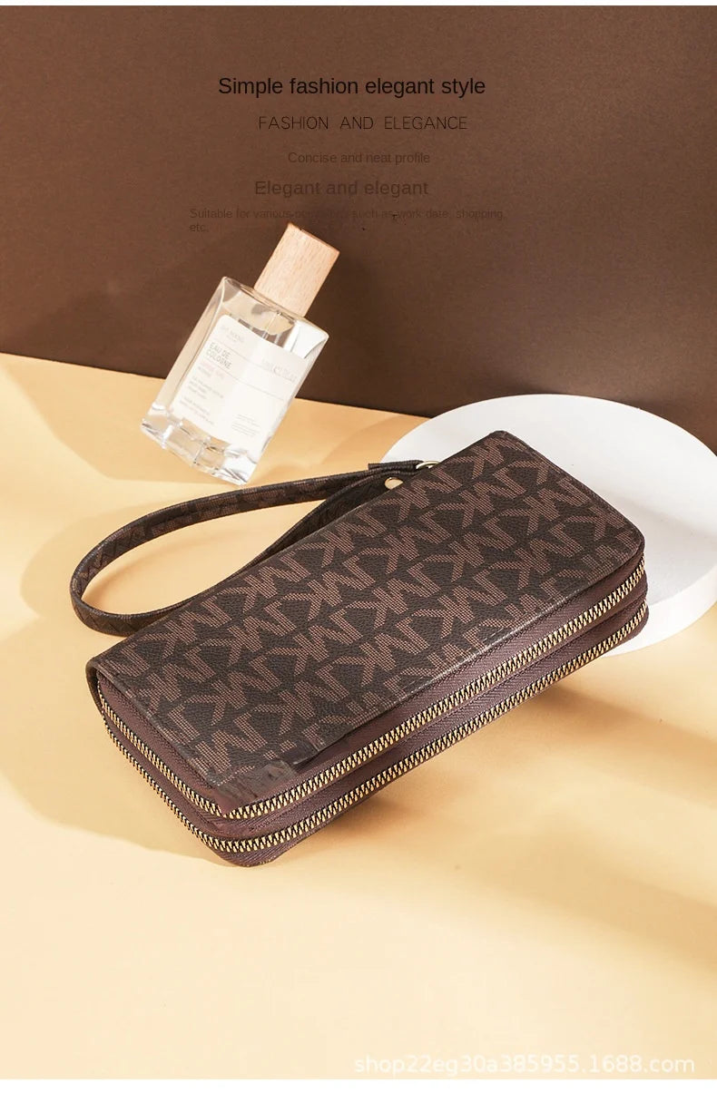 A dark brown patterned PU leather zippered wallet is displayed next to a glass perfume bottle on a light beige surface.