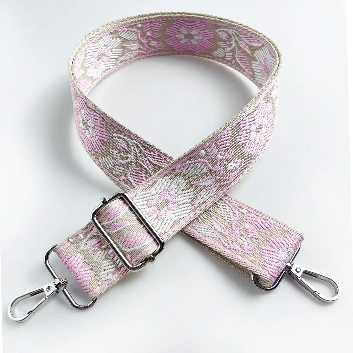 A beige and pink floral patterned adjustable strap for a crossbody bag.