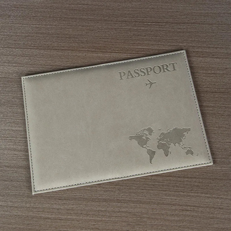 Housse de passeport en cuir PU beige clair avec texte gravé et silhouette de carte du monde, posée sur une surface en bois br