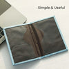A slim blue passport holder with a dark gray interior is shown open on a white surface.