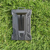 A black slim aluminum metal ID card wallet lying on green grass.