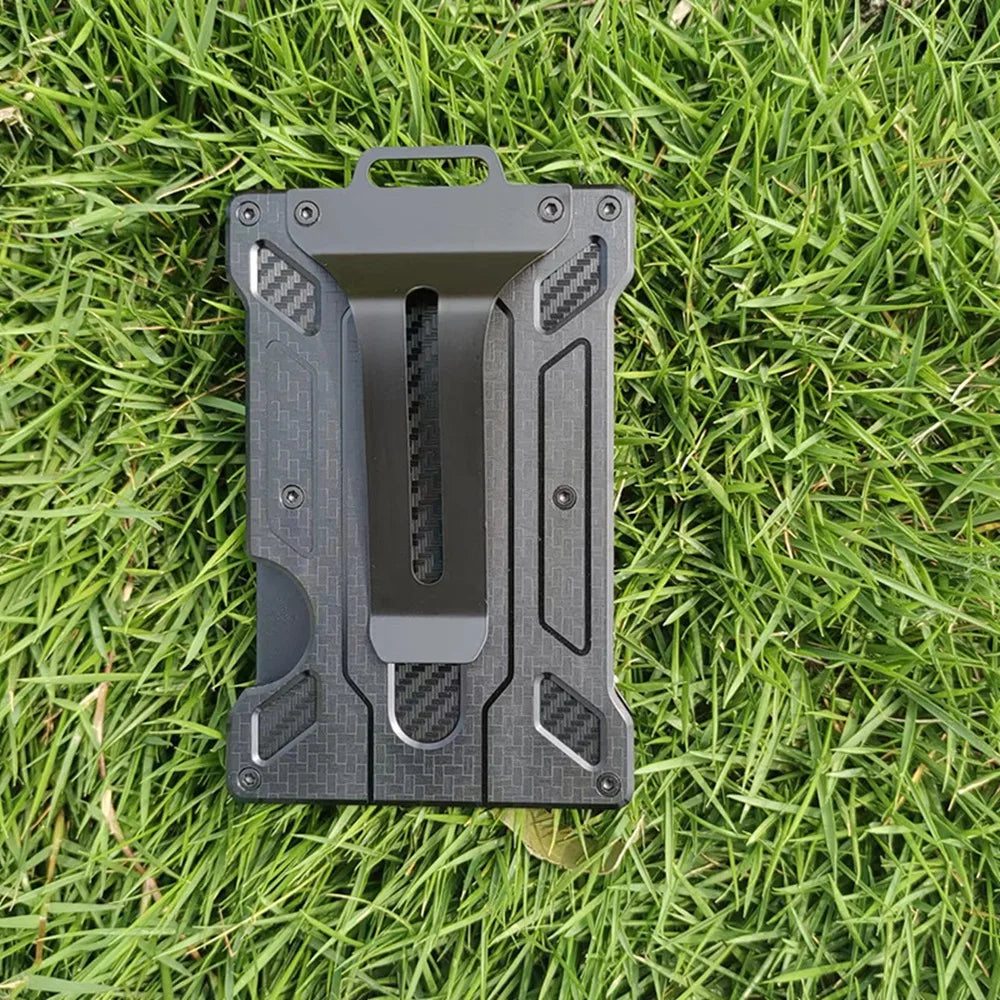 A black slim aluminum metal ID card wallet lying on green grass.