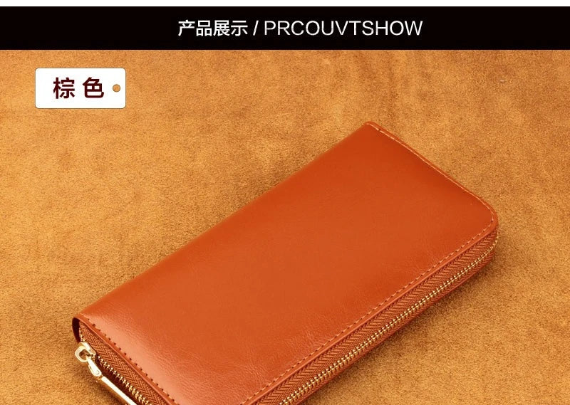 A brown genuine leather zipper wallet shown on a textured orange background.