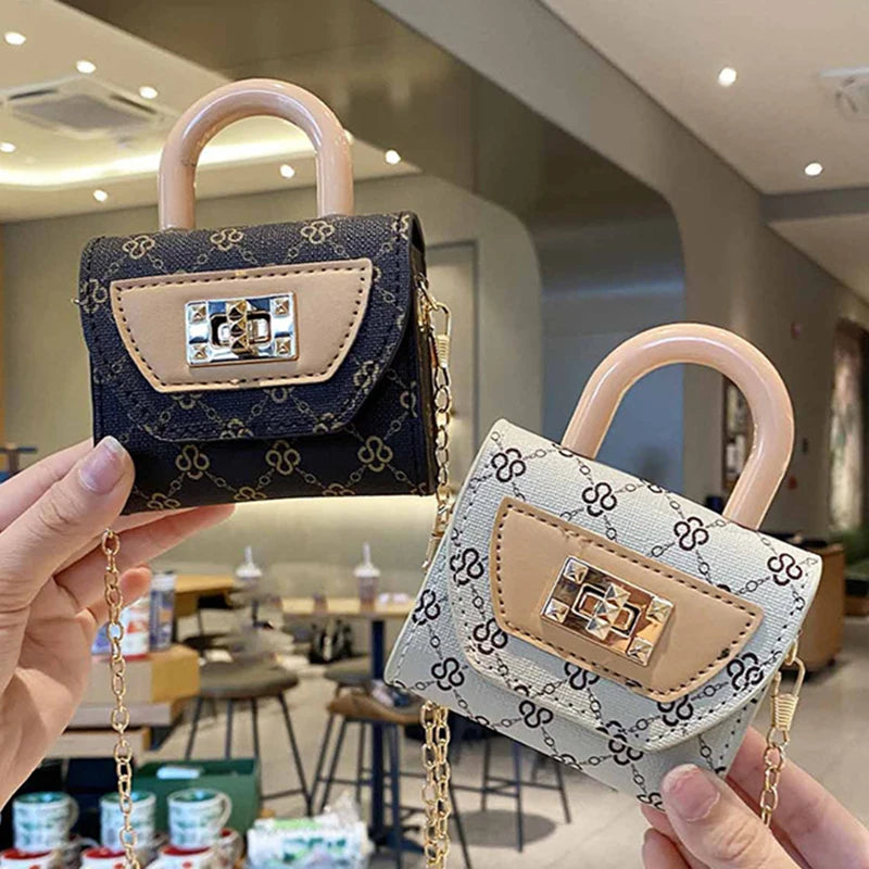 Una mano sostiene un bolso cruz con textura floral y ribete de cuero beige claro y cadena dorada.