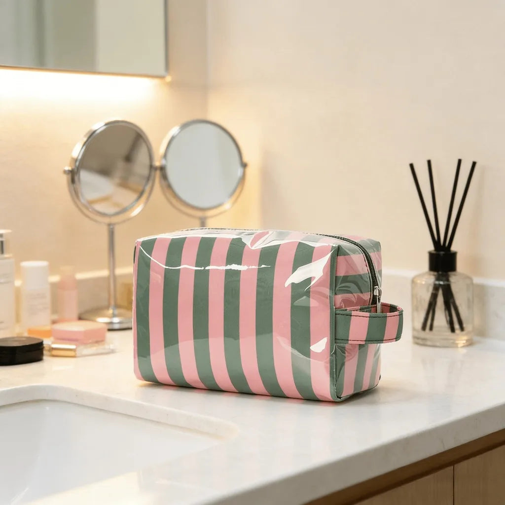 A striped green and pink waterproof cosmetic bag resting on a white countertop next to mirrors.