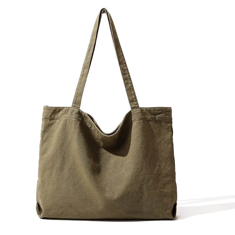 A large olive green canvas shoulder tote bag hanging with straps against a white background.