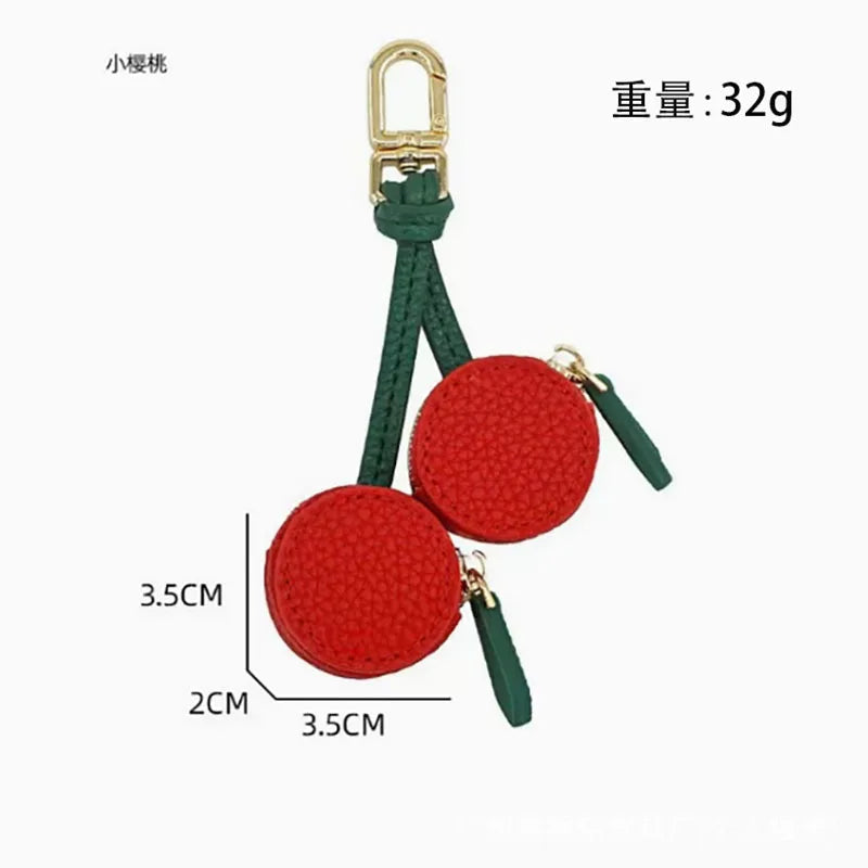 A red fruit-shaped PU leather coin purse keychain with a green fabric strap and gold clasp.