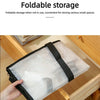 A hand holds a large transparent woven storage bag with black double zippers inside a wooden box.