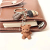 A brown leather wallet with a gold-colored bear pendant keychain attached to a leather tag.