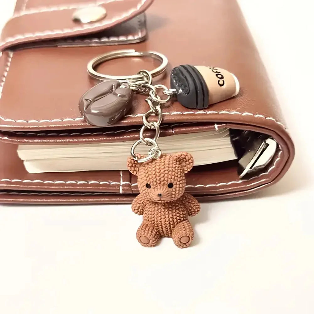 A brown leather wallet with a gold-colored bear pendant keychain attached to a leather tag.
