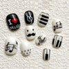 A set of press-on nails featuring various designs including black and white stripes, heart motifs, and musical notes on a whi