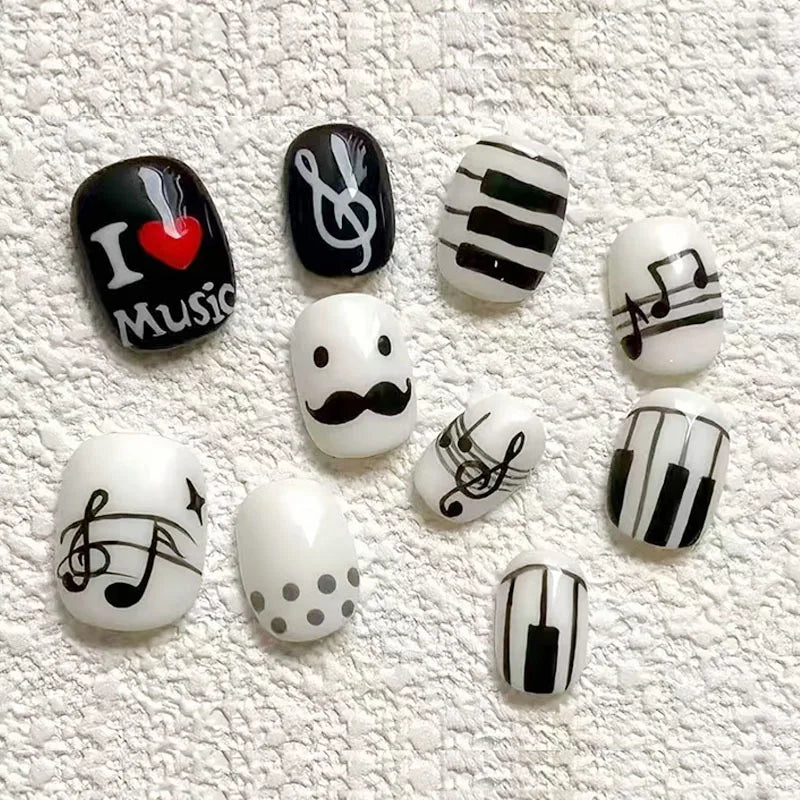 A set of press-on nails featuring various designs including black and white stripes, heart motifs, and musical notes on a whi