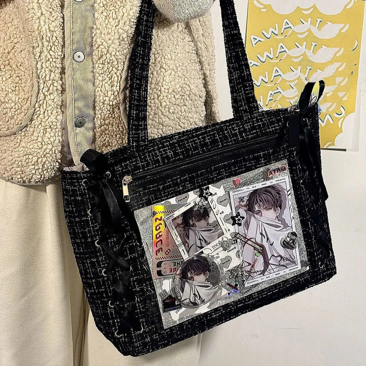 A black mesh shoulder tote bag featuring transparent inserts with illustrations.