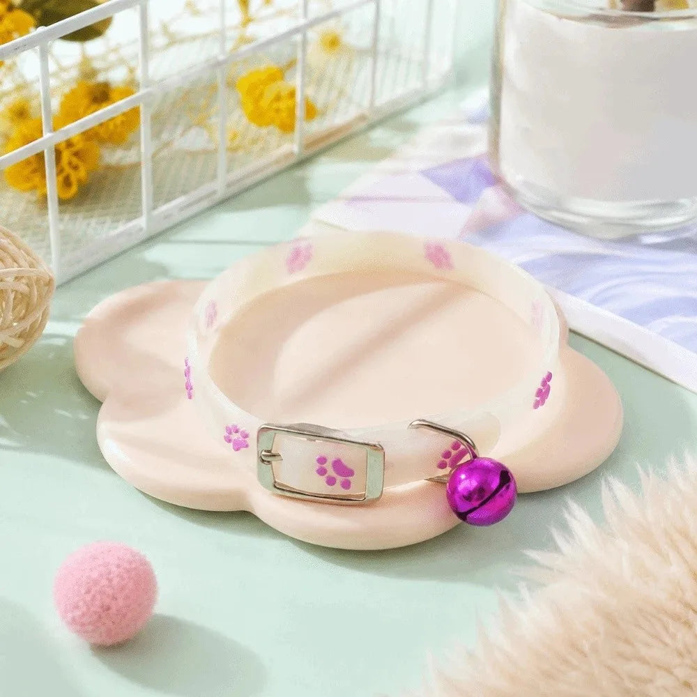 A light pink glow-in-the-dark pet collar for dogs and cats resting on a green surface.