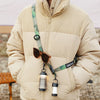 A beige outdoor jacket features a green strap with sunglasses and a flashlight attached.
