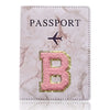 Portada de pasaporte marmolado rosa con una letra B dorada y un ícono de avión.