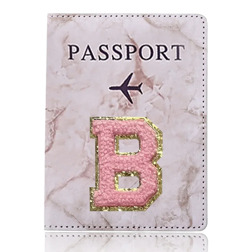 Portada de pasaporte marmolado rosa con una letra B dorada y un ícono de avión.