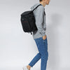 A person wearing a grey hoodie and jeans is carrying an olive green insulated thermal cooler backpack.