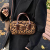 Braune Leopardenmuster-Designer-Hobo-Tasche, getragen von einer Person in einem schwarzen Mantel.