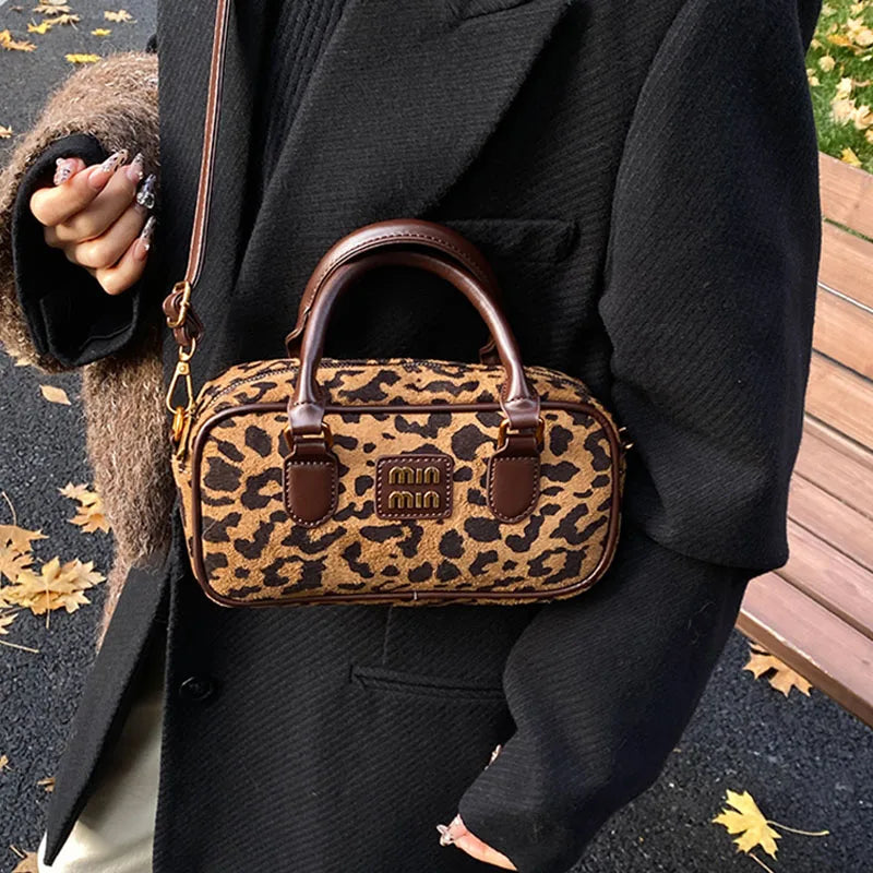 Braune Leopardenmuster-Designer-Hobo-Tasche, getragen von einer Person in einem schwarzen Mantel.