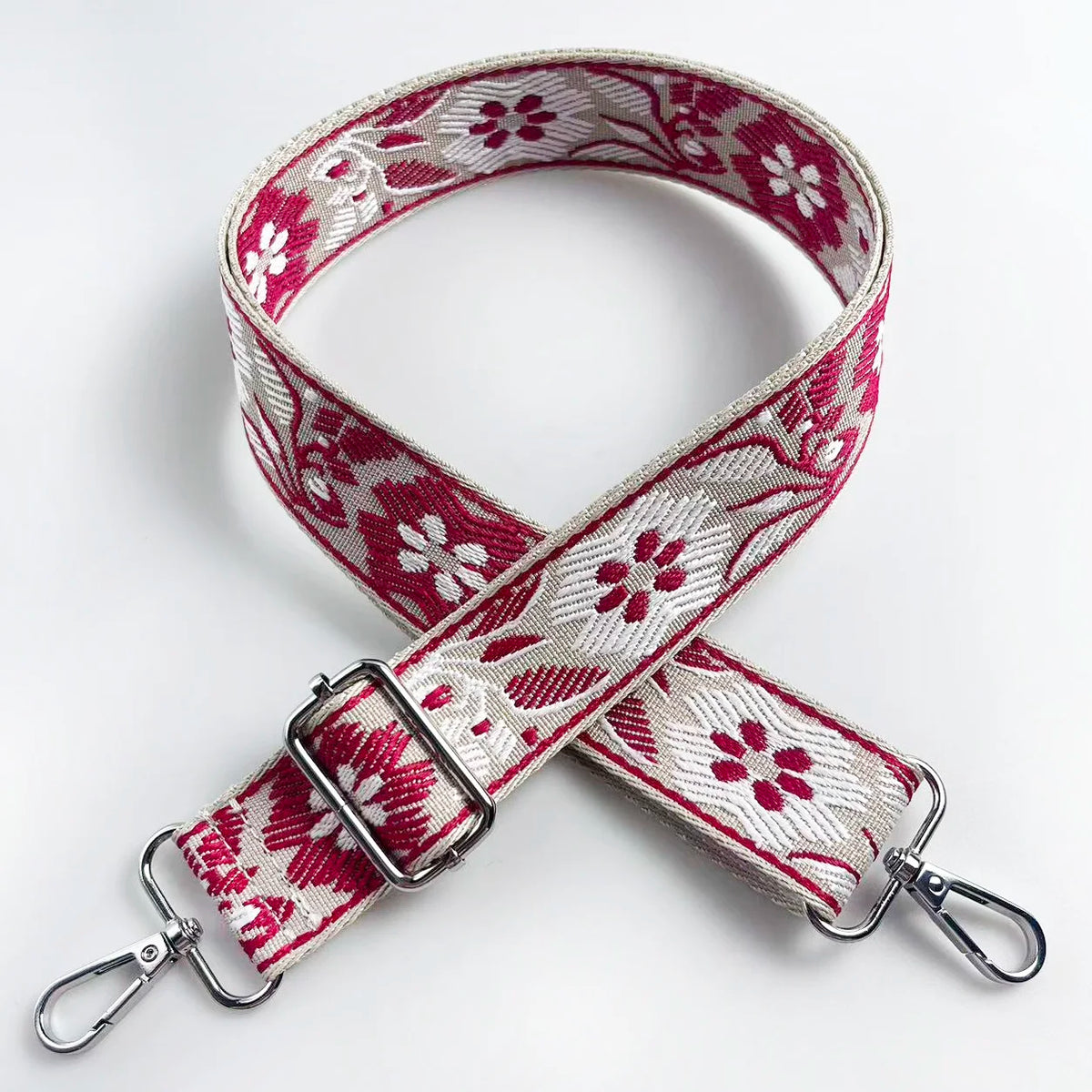 A pink and white floral jacquard strap for a crossbody bag, shown folded on a white background.