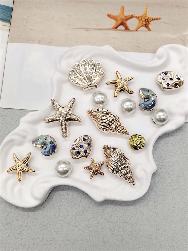 A collection of gold and silver conch shell and starfish jewelry charms displayed on a white ceramic dish.