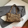 A leopard print casual tote bag resting on a gray blazer on a white surface.